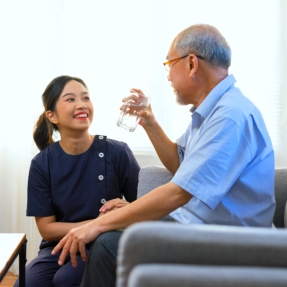 caregiver giving water to the elderly